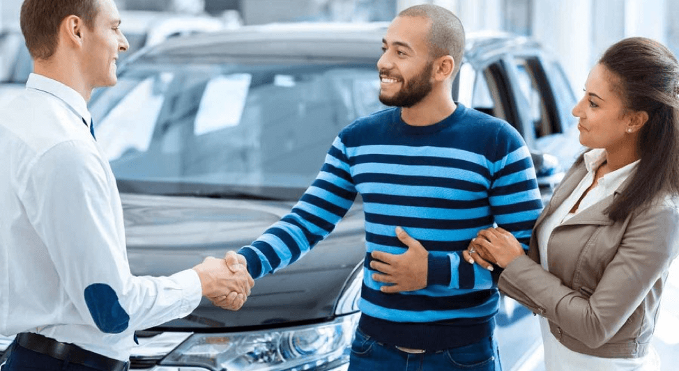 concessionnaire automobile serrant la main d'un couple