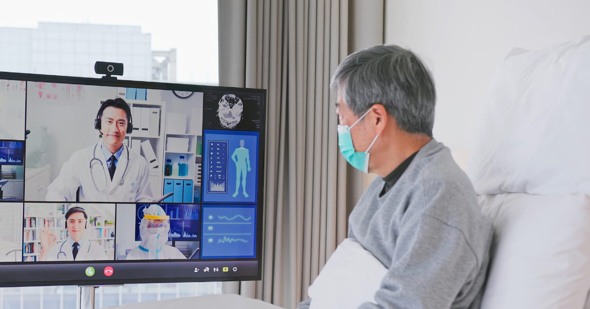 A patient telemedicine experience with an elderly man sitting in bed in a video call with doctors.