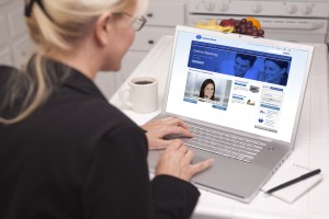 Über die Schulter der Frau in der Küche mit Laptop - Online-Chat mit Krankenschwester oder Arzt auf dem Bildschirm.