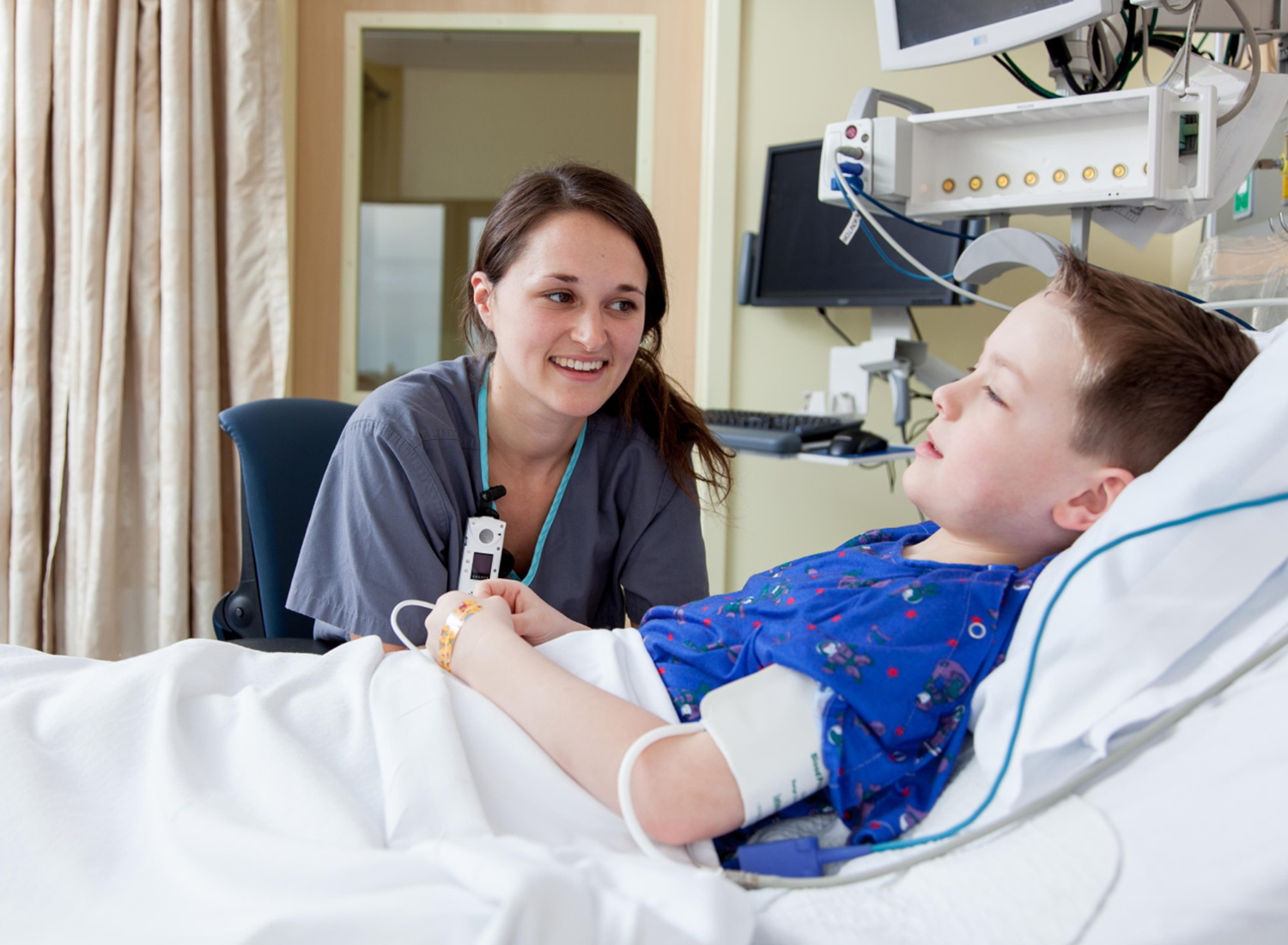 female doctor with boy in bed in hospital