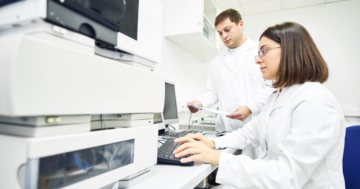 Pharmaceutical Industry staff entering data into a computer in their lab.