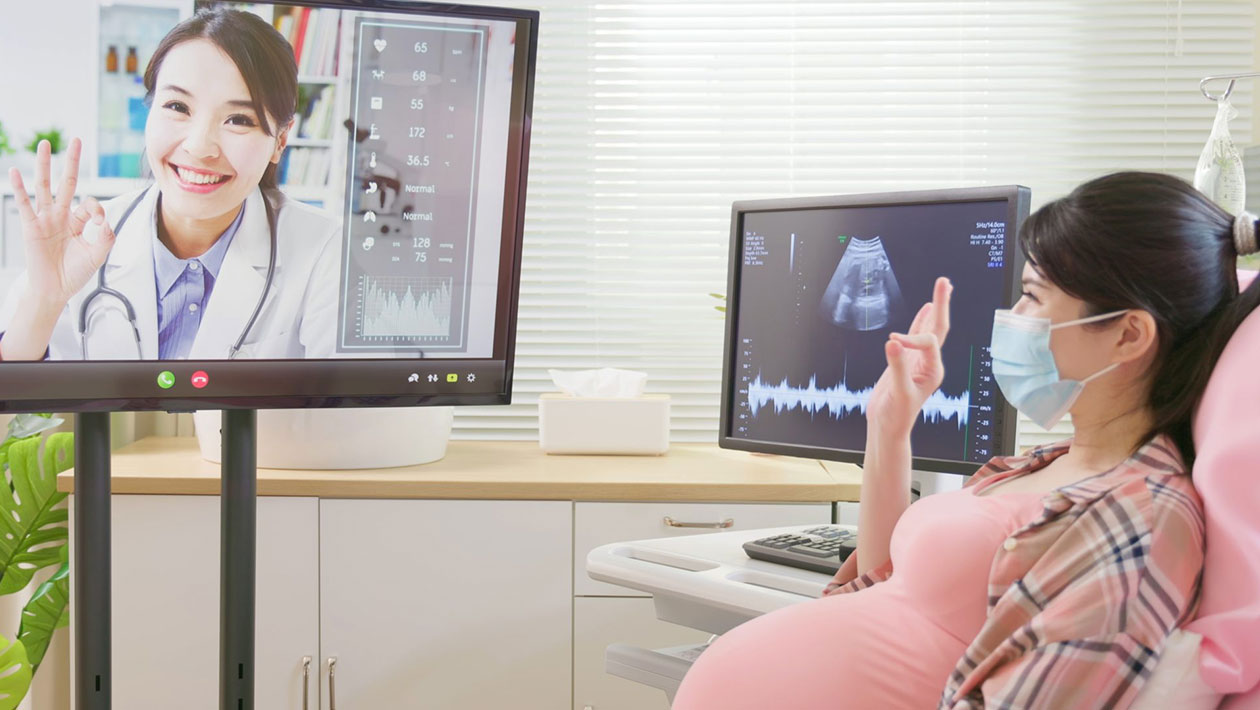 doctor remote-monitoring pregnant woman in hospital bed via video call