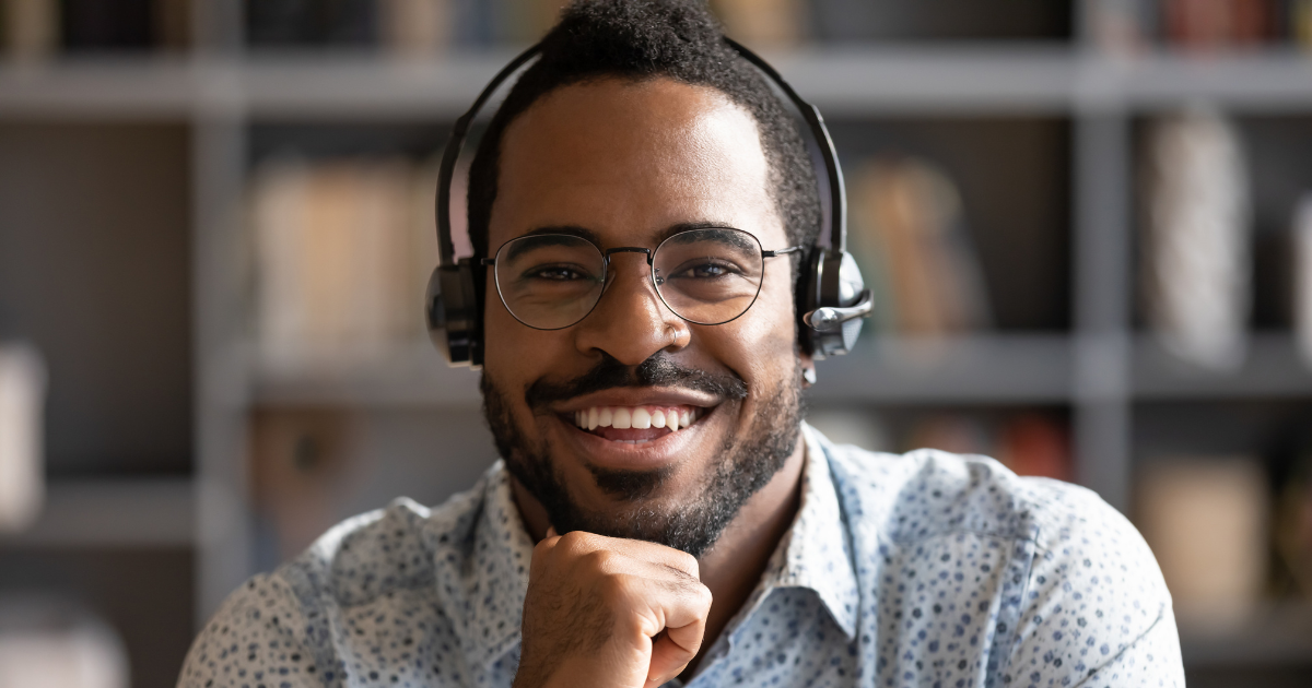 Adult male wearing headphones and smiling. Depicted to be using translation services.