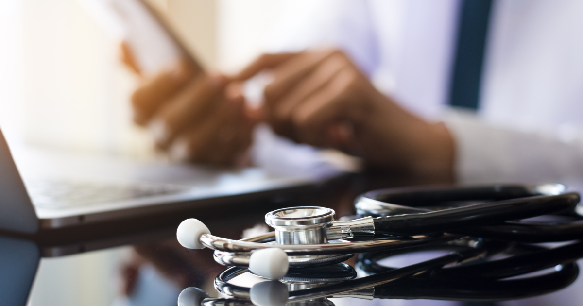 Doctor utilizing Electronic Health Record (EHR) integration using his laptop and phone.