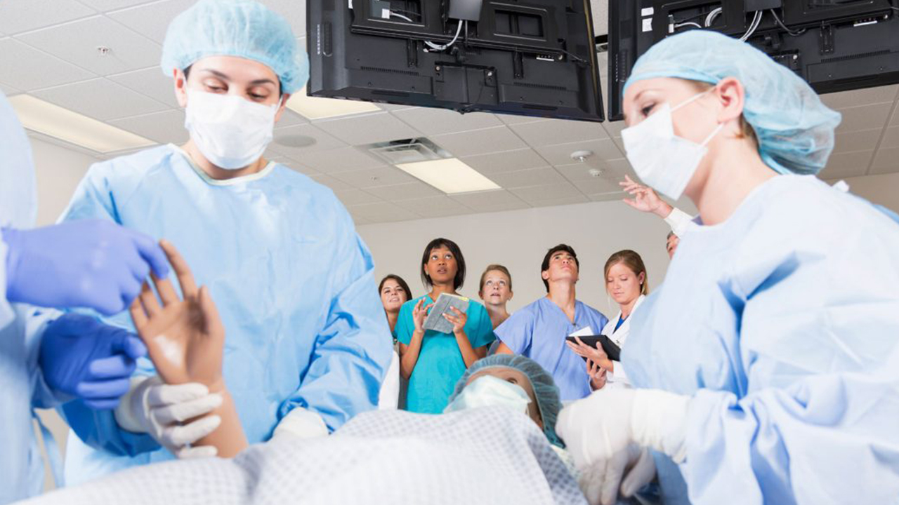 Ärzte bei der Untersuchung von Patienten mit Studenten im Hintergrund