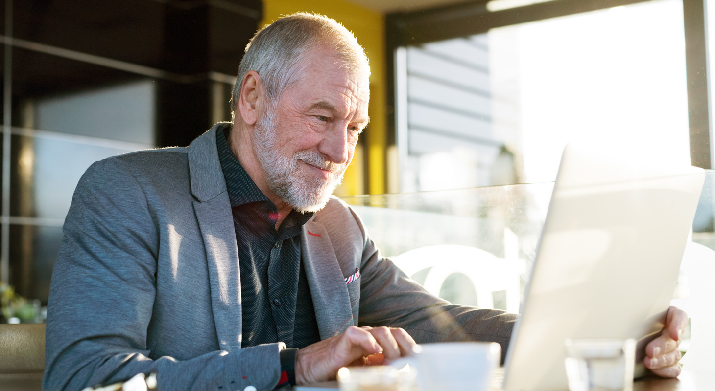 Senior zakenman werkt op laptop in café